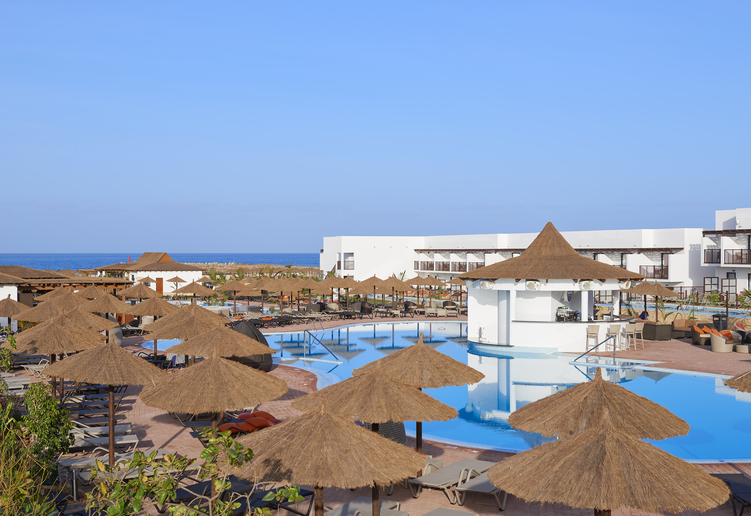 a pool with straw umbrellas and chairs
