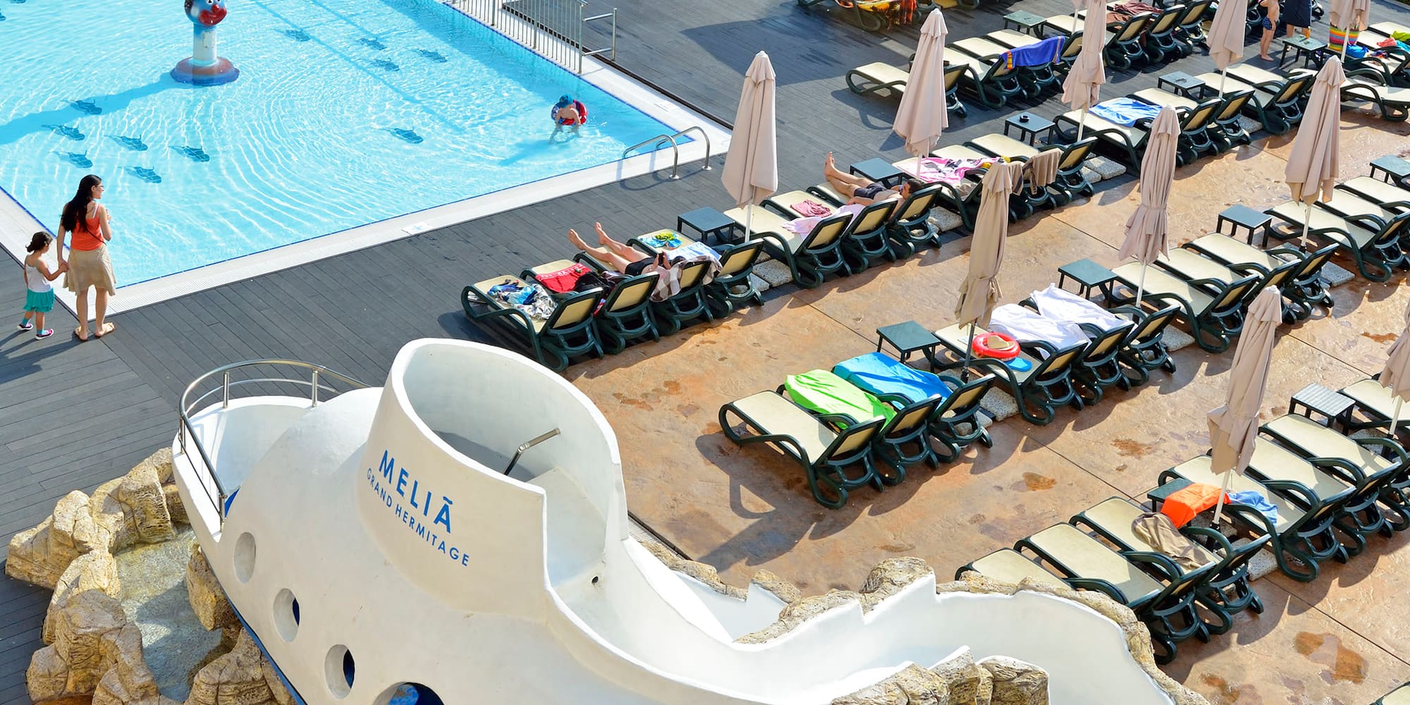 a pool with a boat shaped object and people around it
