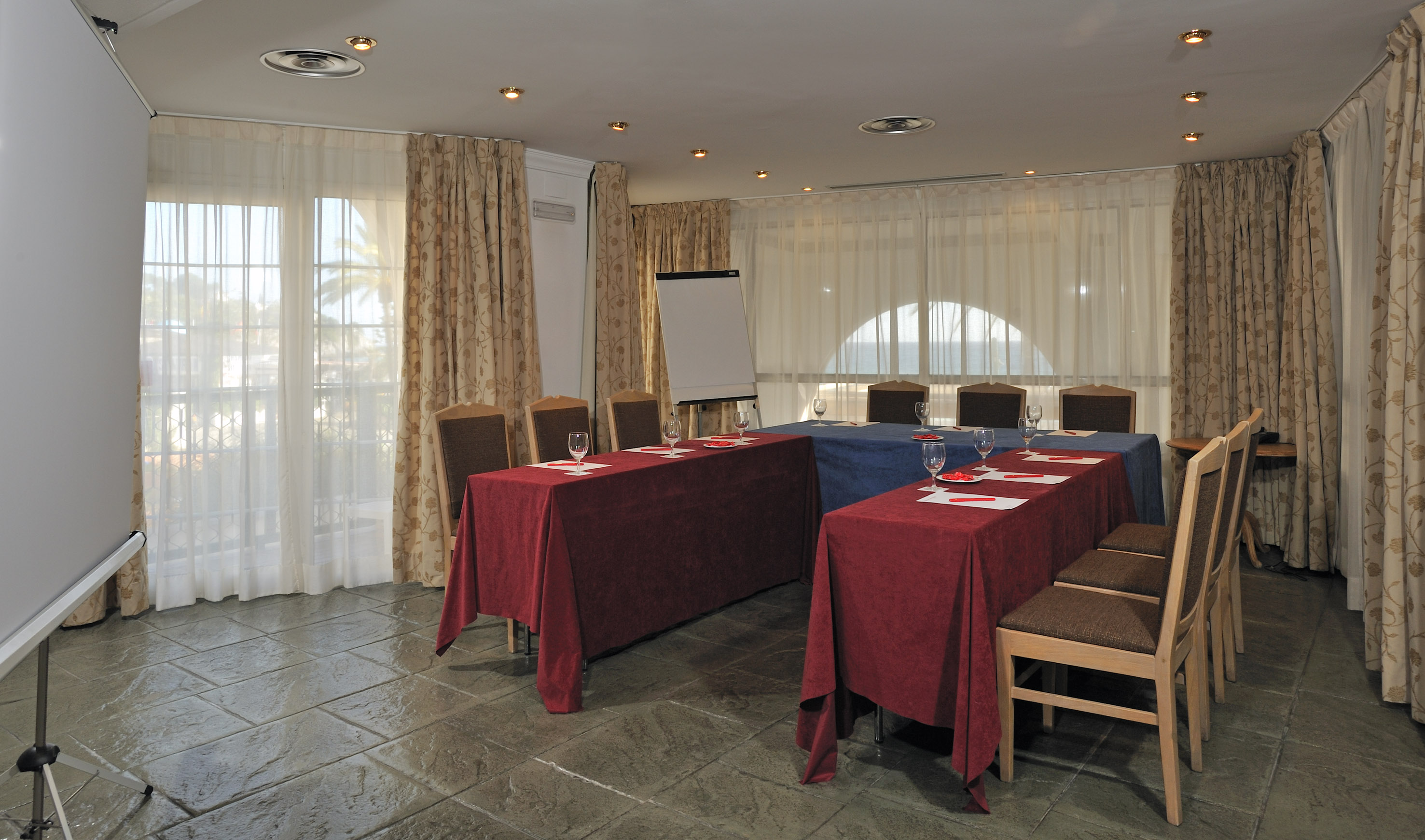 Hotel meeting room with tables, chairs, projector screen, and whiteboard.