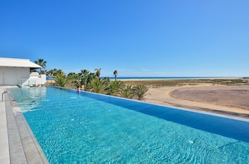 a pool with palm trees and a beach in the background