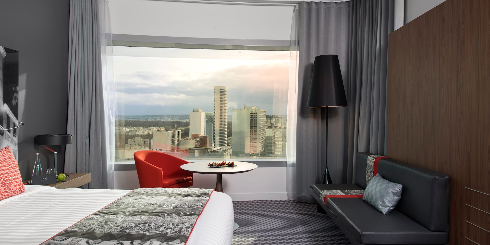 a room with a bed and a table and a window with a city view