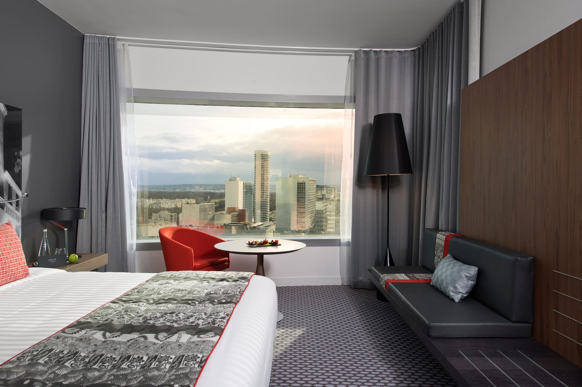 a room with a bed and a table and a window with a city view