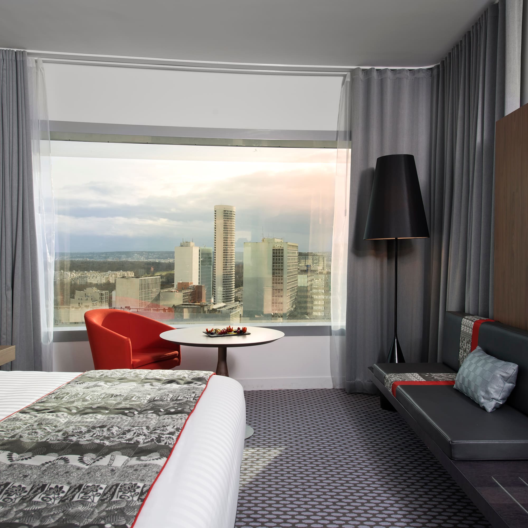 a room with a bed and a table and a window with a city view