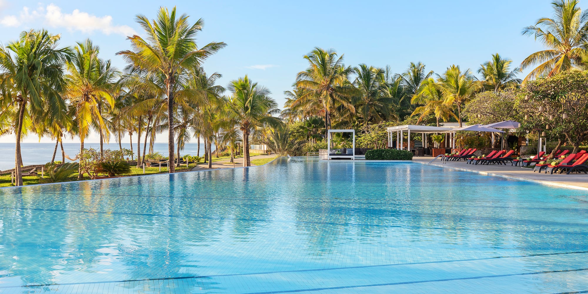 a pool with palm trees and a gazebo