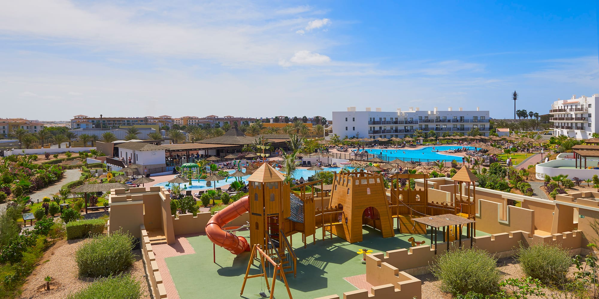 a playground with a slide and a pool in the background