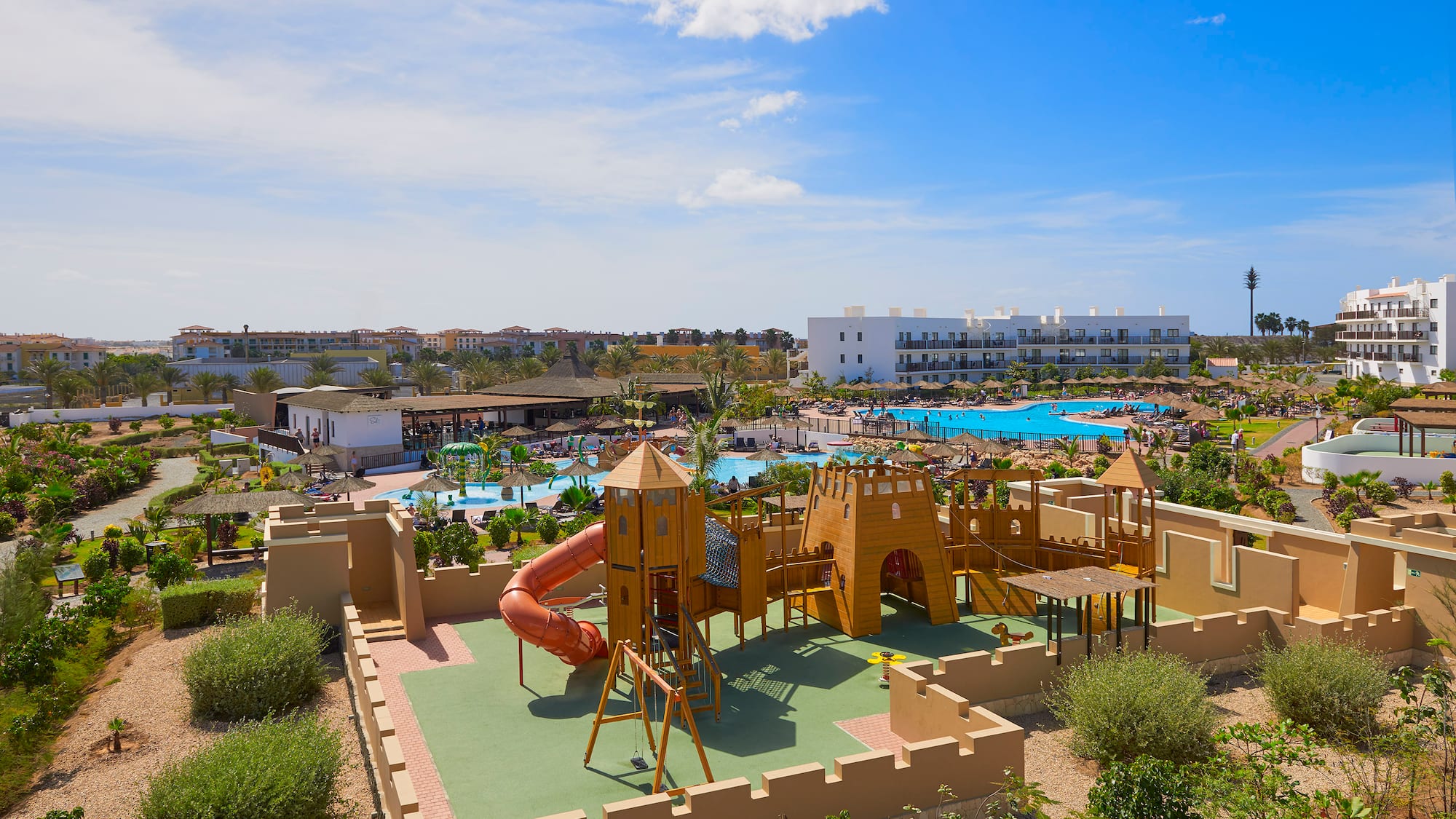 a playground with a slide and a pool in the background