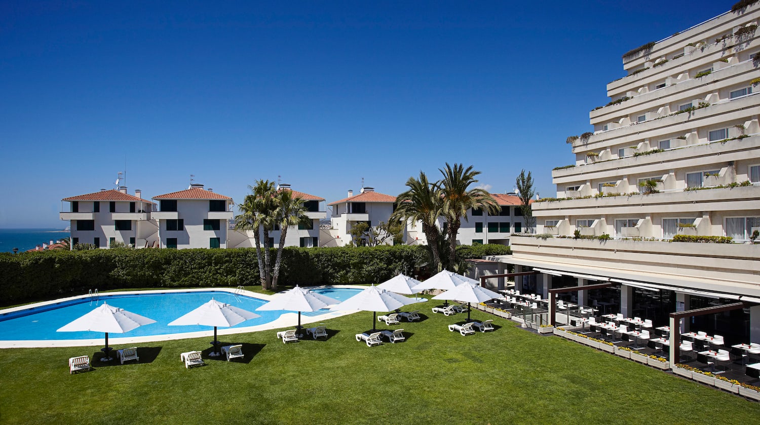 a pool with umbrellas and lounge chairs in front of a building