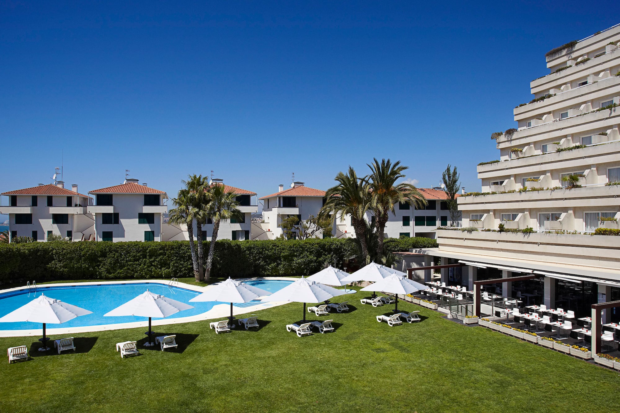 a pool with umbrellas and lounge chairs in front of a building