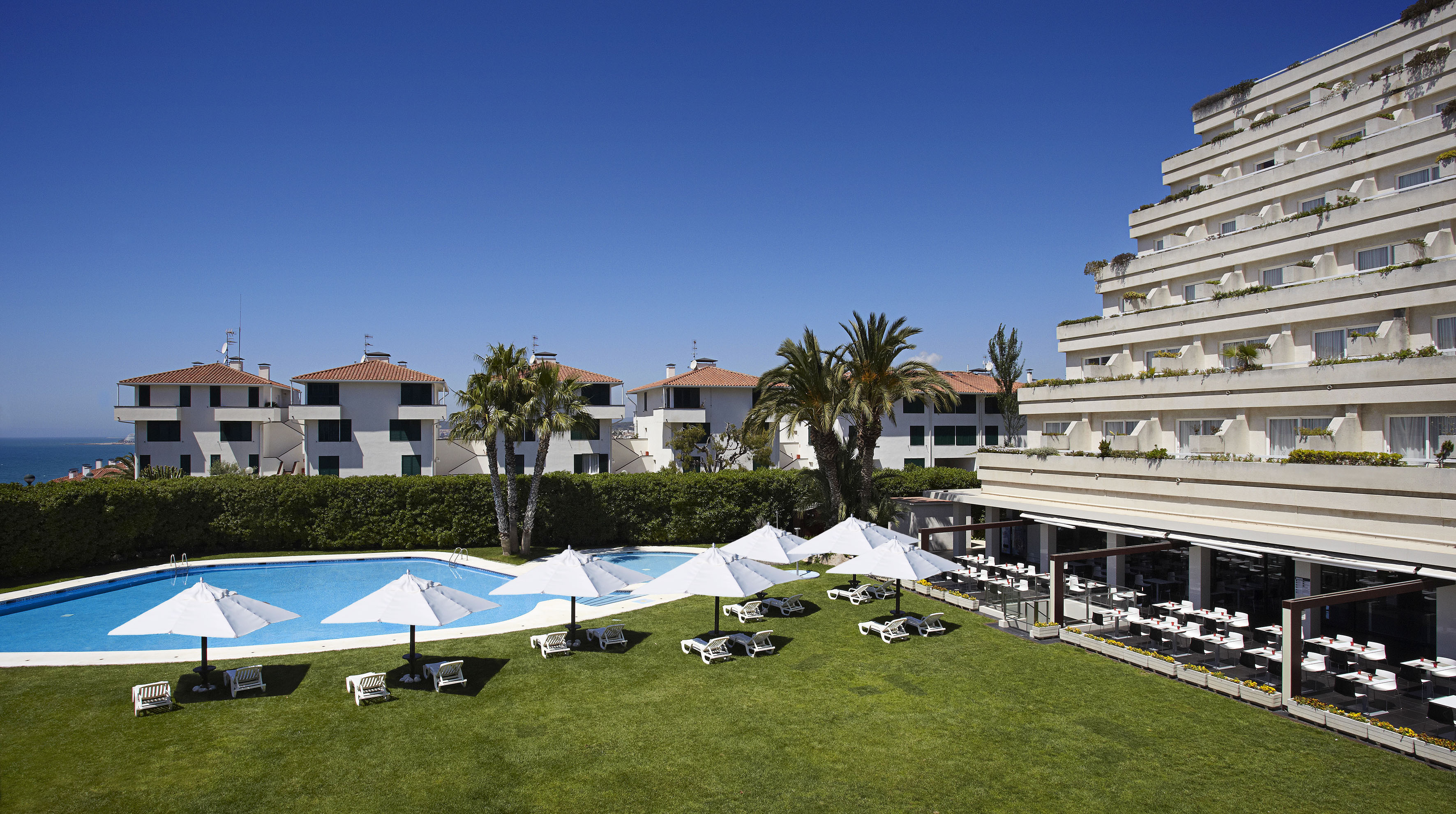 a pool with umbrellas and lounge chairs in front of a building
