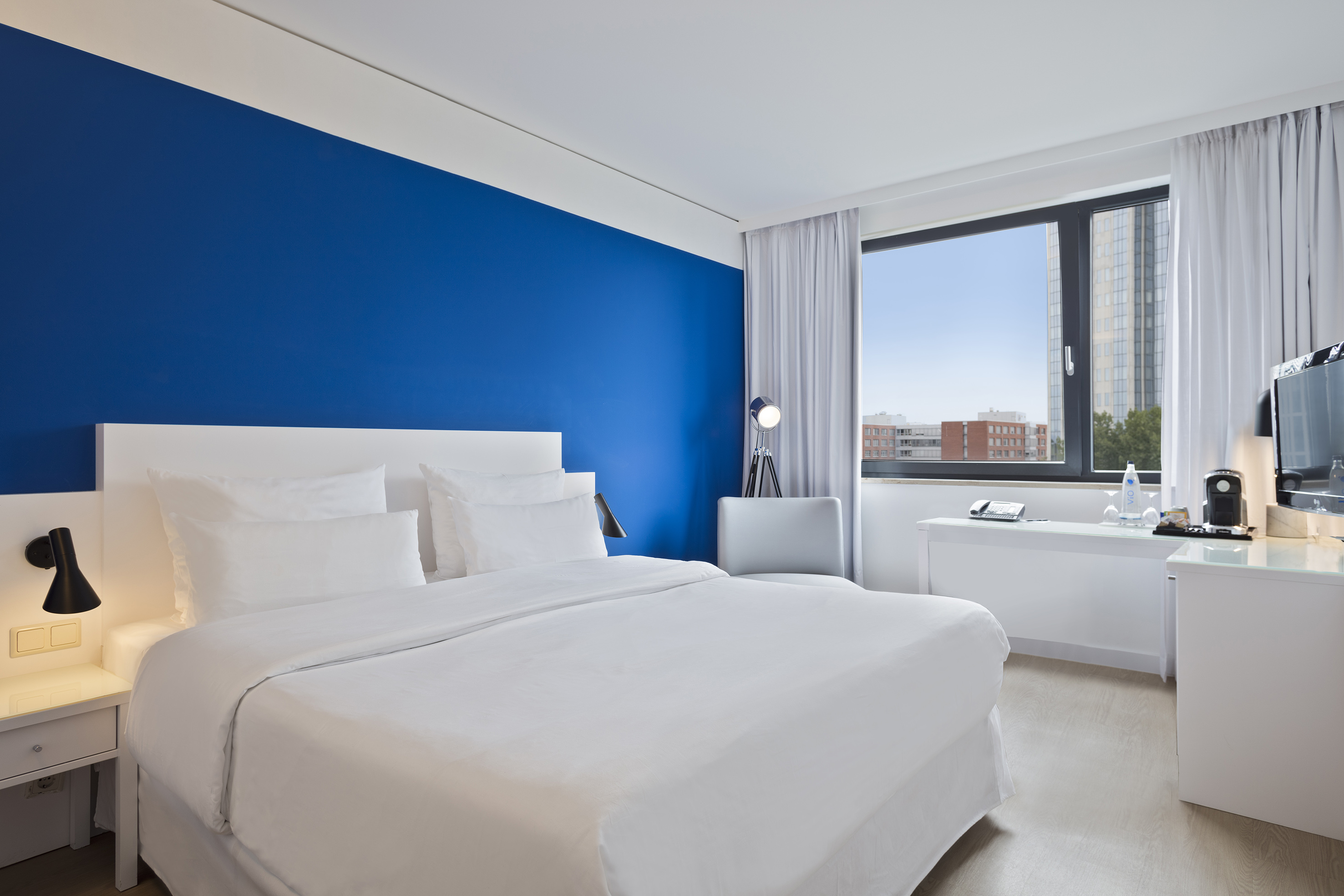 a bedroom with a blue wall and white bedding