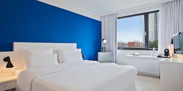a bedroom with a blue wall and white bedding
