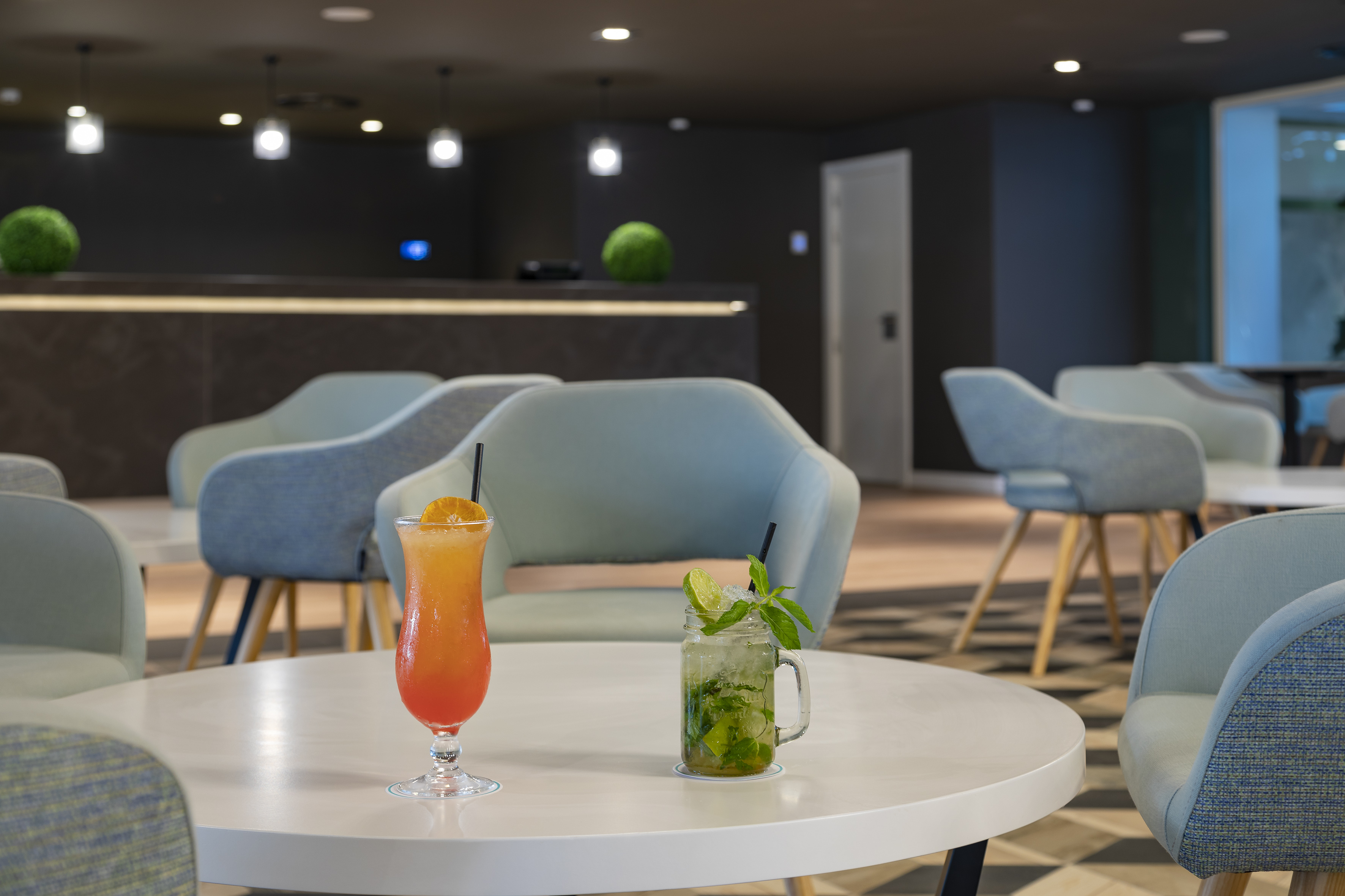 Mojito and tropical cocktail on a white table in a contemporary lounge bar.