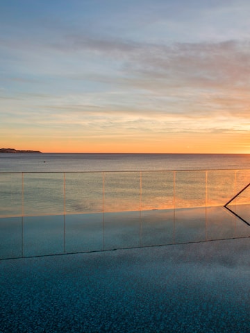 a pool with a railing and a body of water in the background
