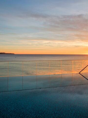 a pool with a railing and a body of water in the background