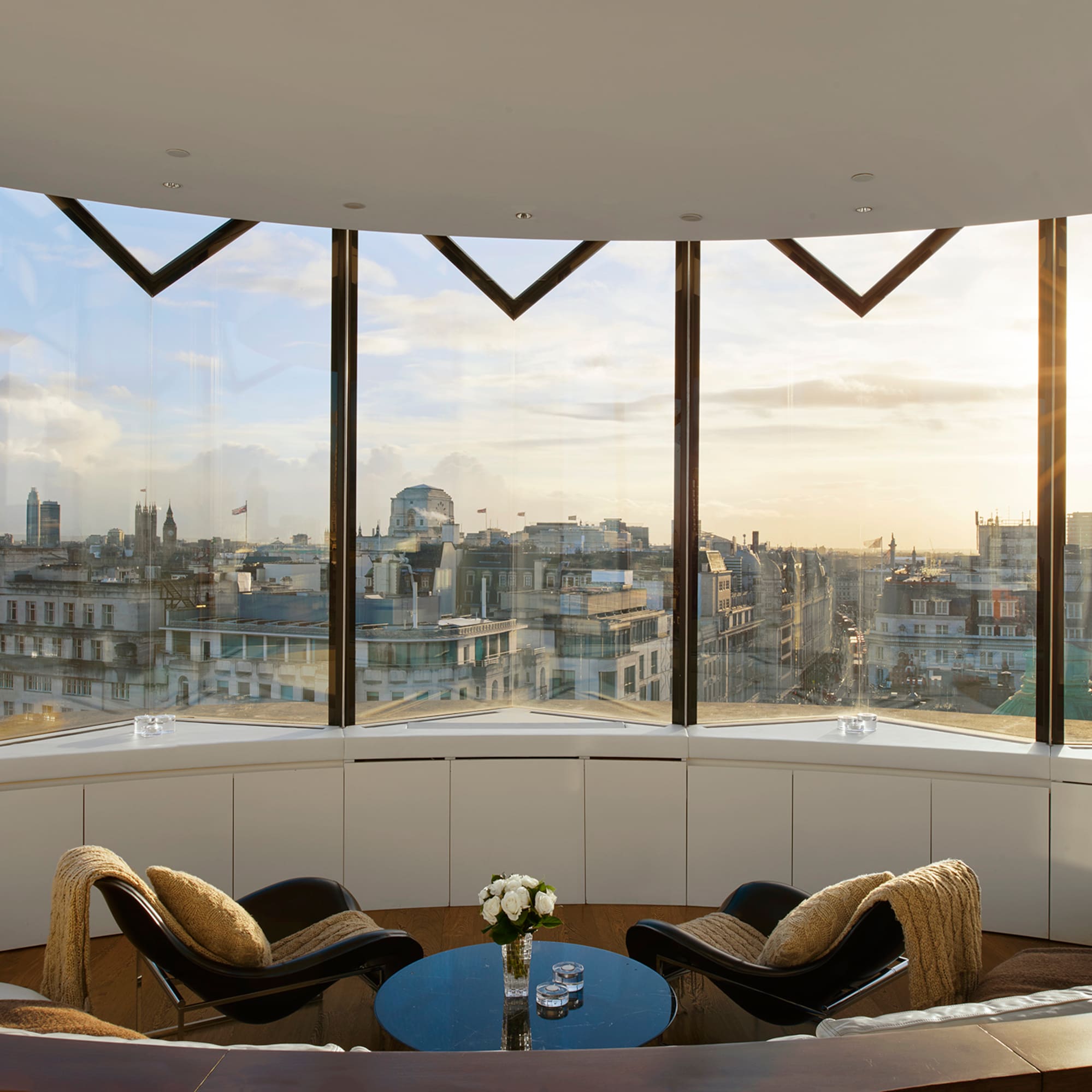 Modern London apartment with panoramic cityscape and London Eye at sunset.