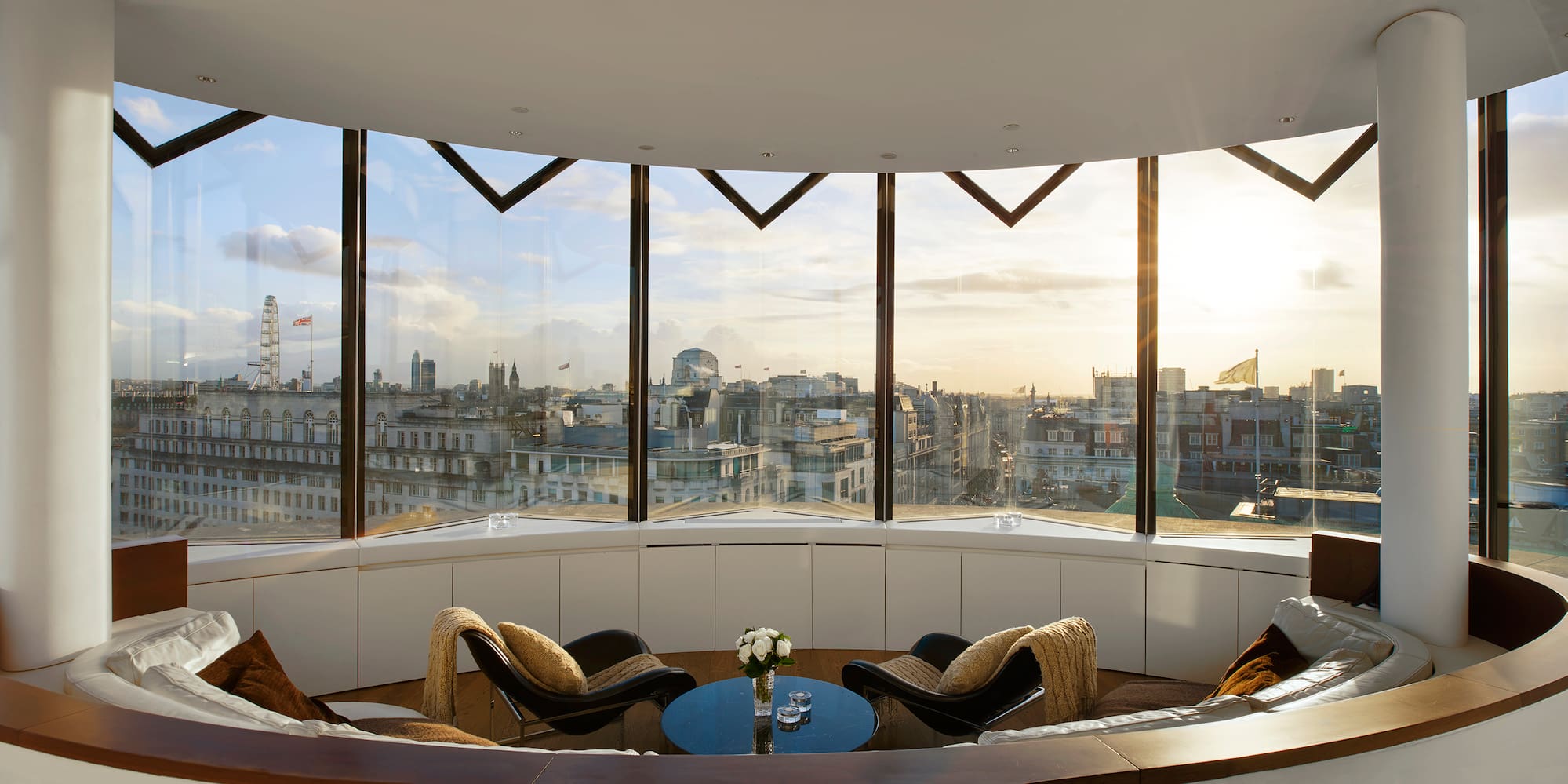 Modern London apartment with panoramic cityscape and London Eye at sunset.