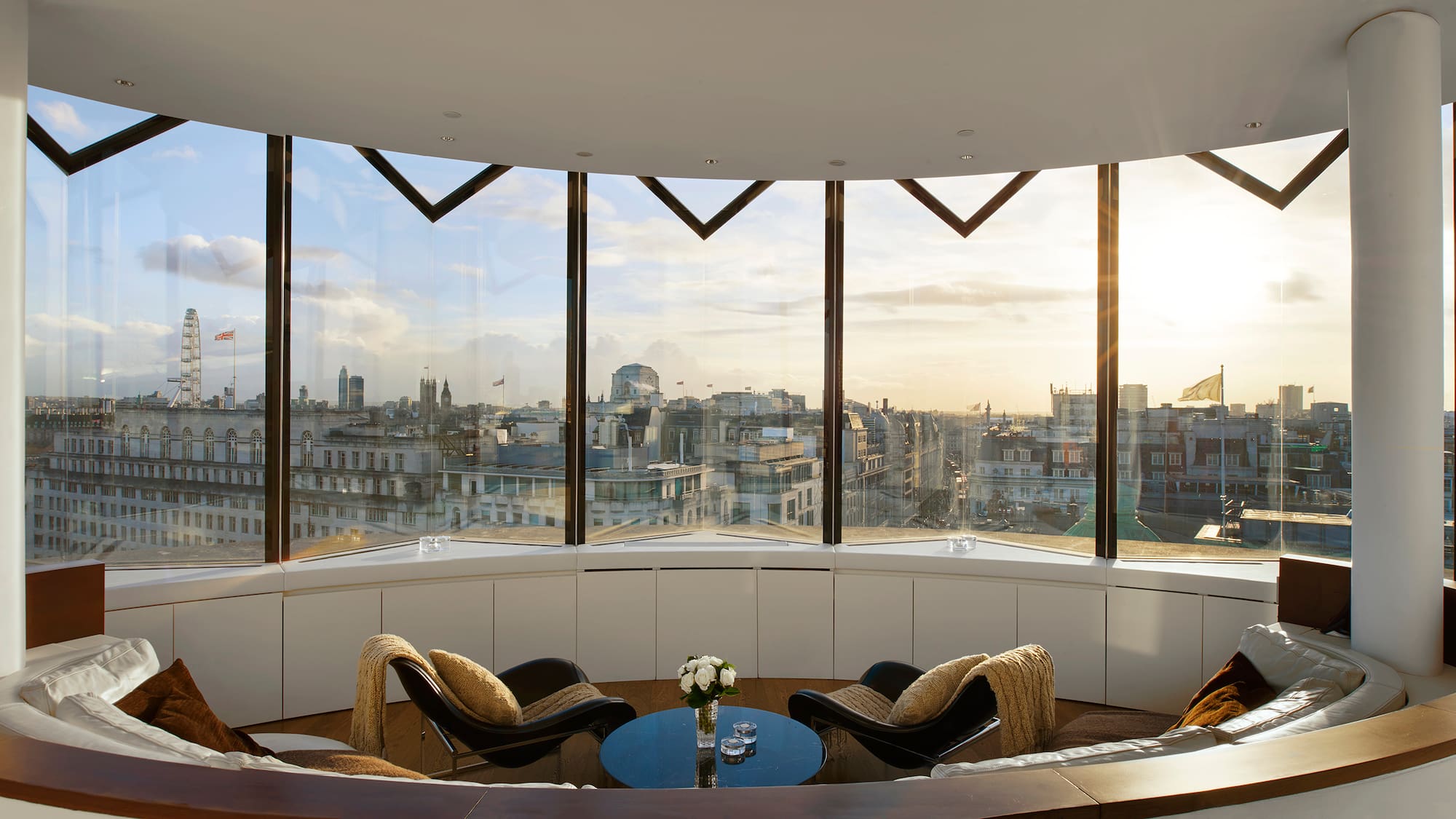 Modern London apartment with panoramic cityscape and London Eye at sunset.