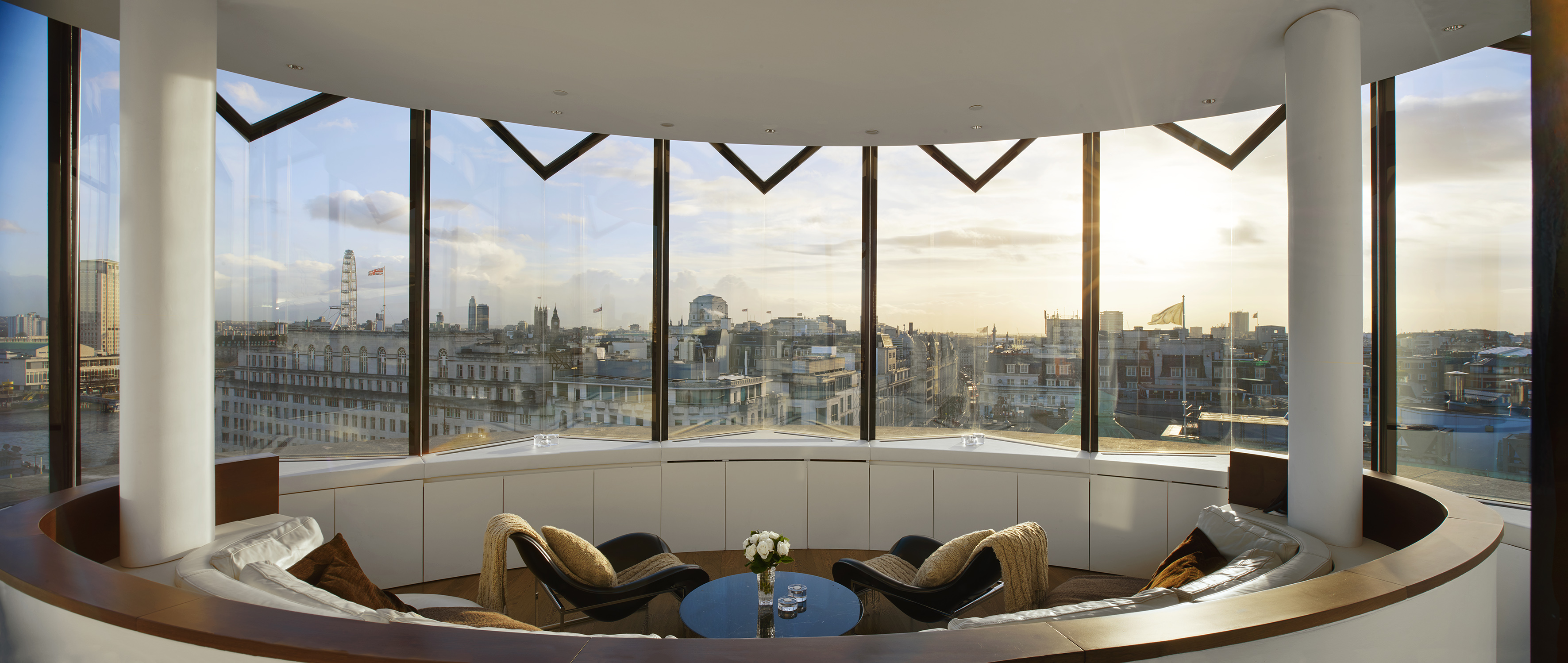 Panoramic London penthouse lounge with city skyline, London Eye, and sunset view.
