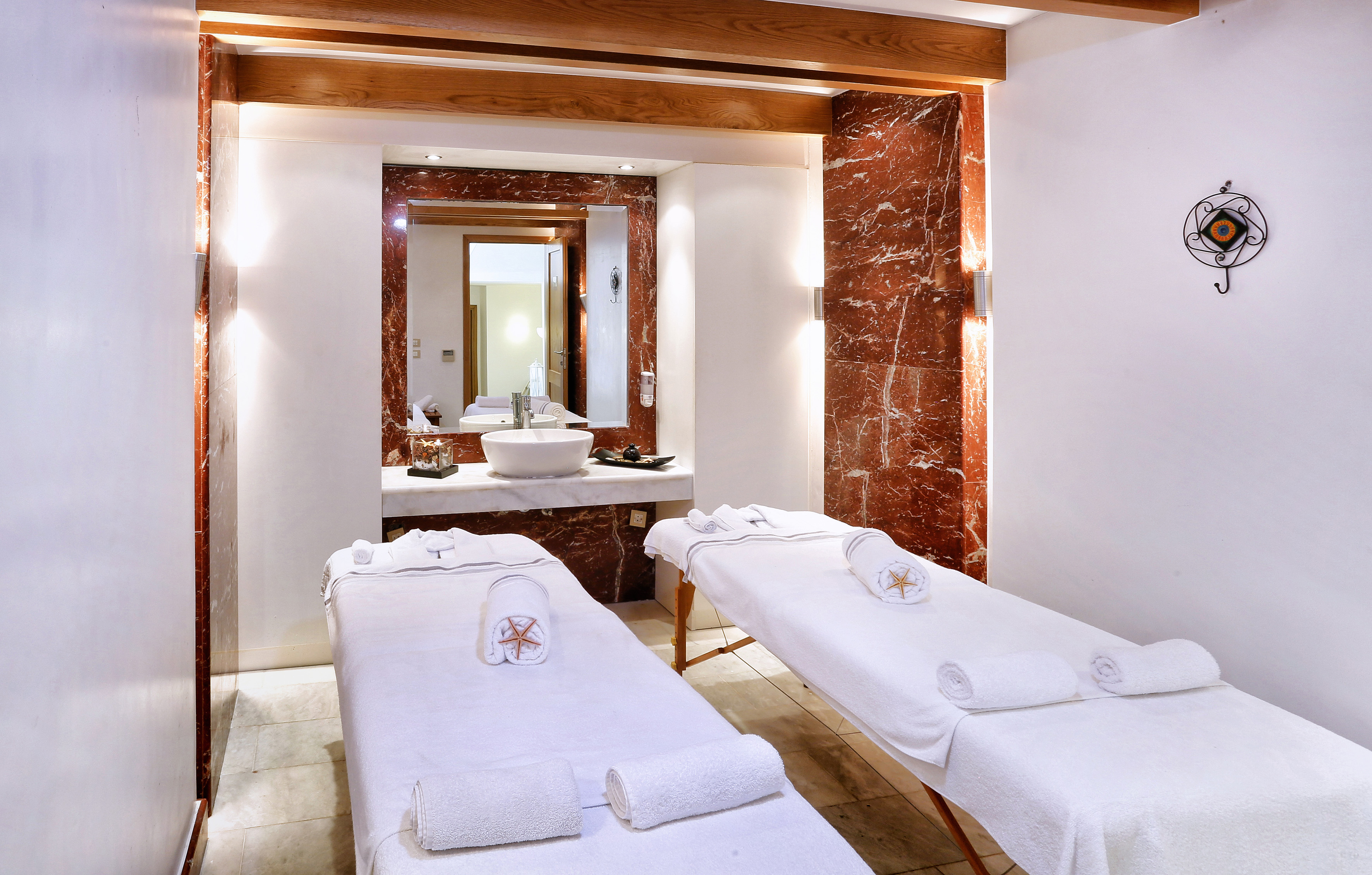 Luxurious spa treatment room with two massage tables and red marble details.