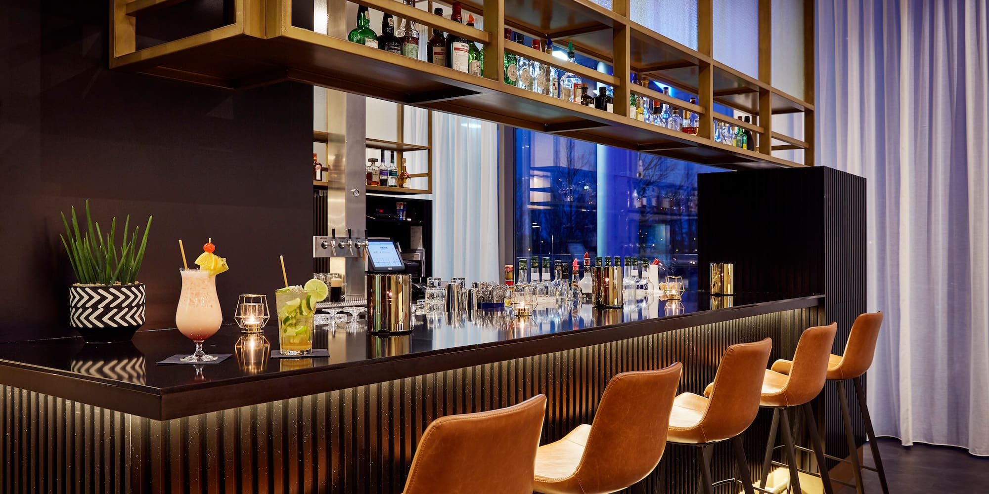 a bar with a row of chairs and drinks