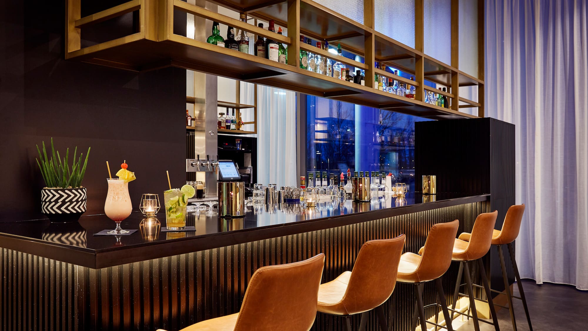 a bar with a row of chairs and drinks