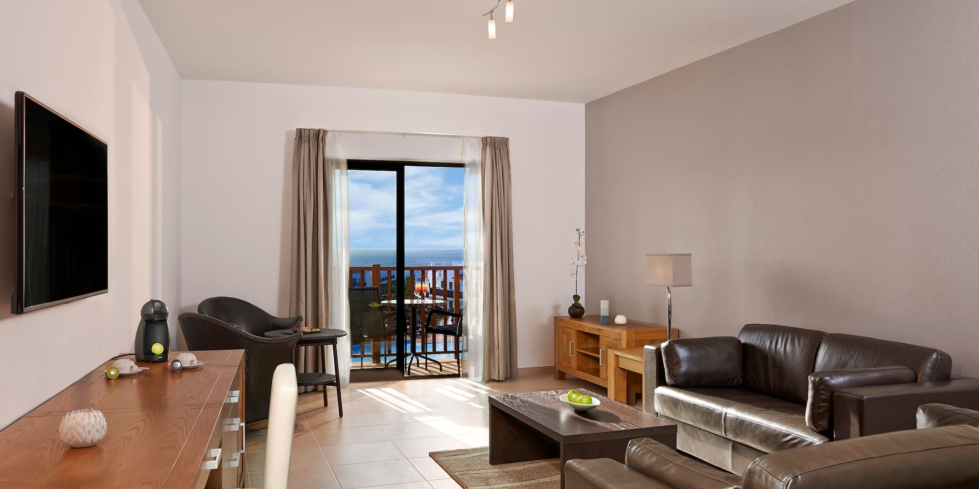 a living room with a table and chairs and a balcony