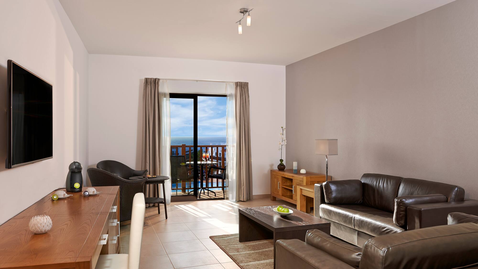 a living room with a table and chairs and a balcony