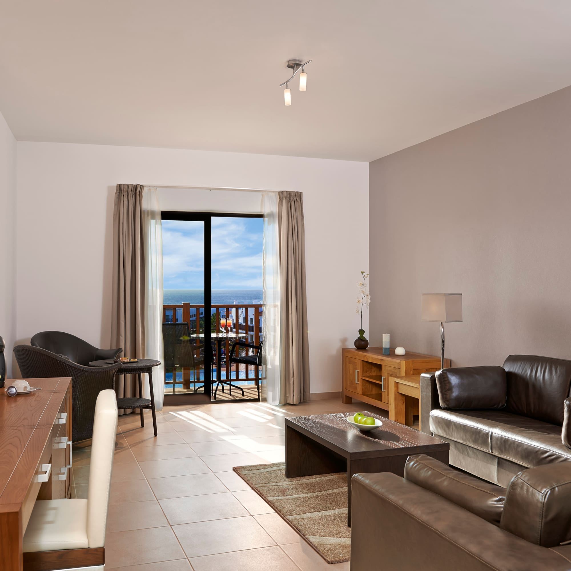 a living room with a table and chairs and a balcony