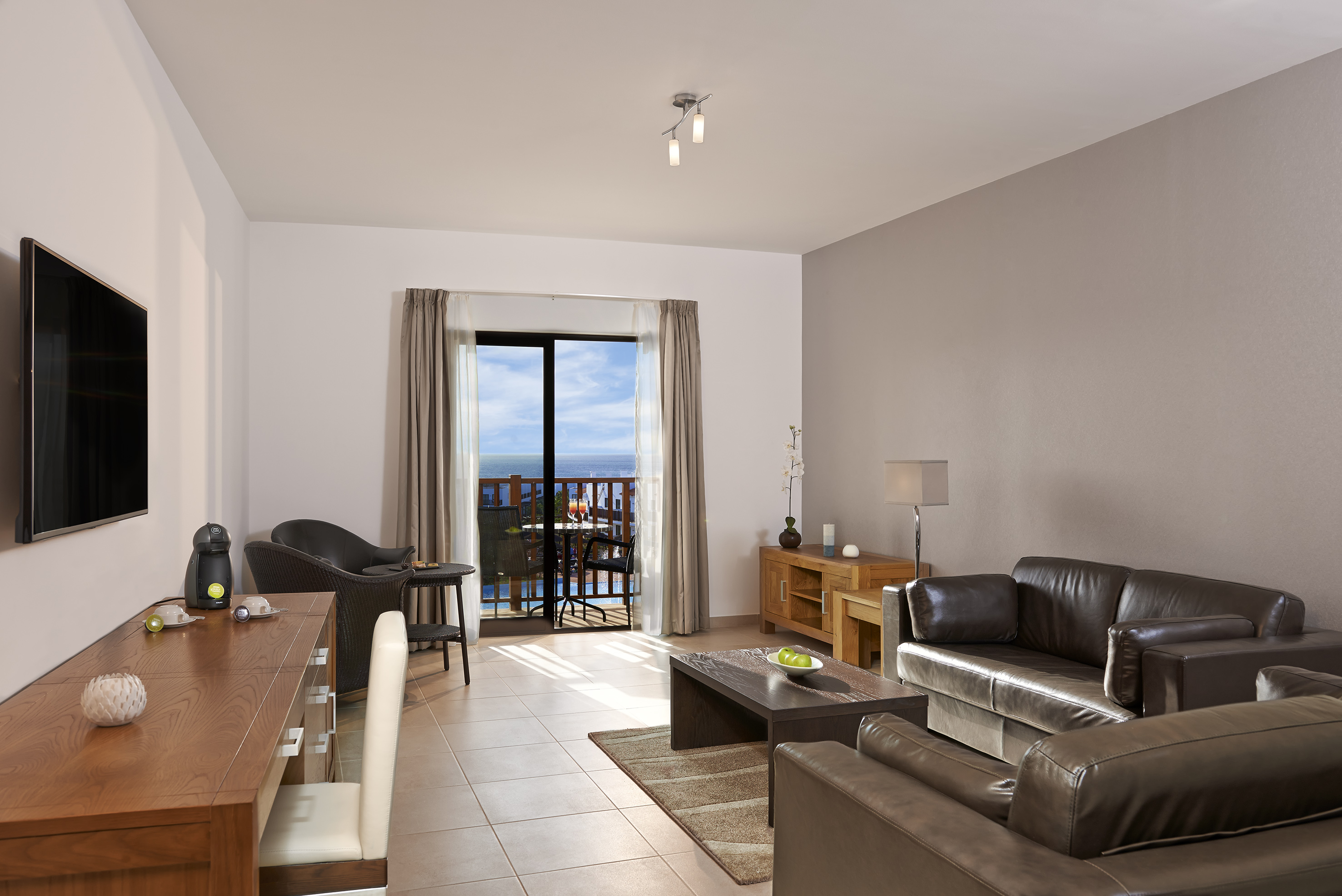 a living room with a table and chairs and a balcony