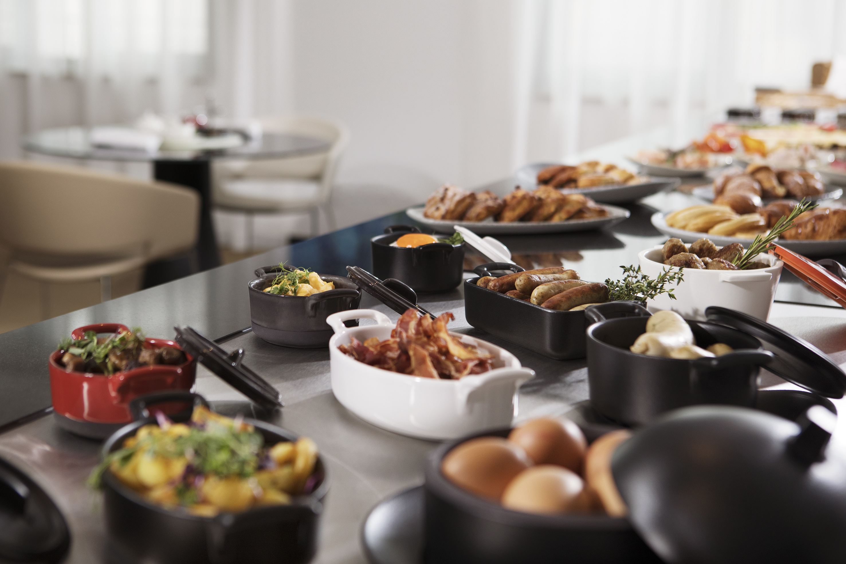 Breakfast buffet: eggs, bacon, sausages, and pastries on a long table. - Nechte se unést světem výjimečnosti a exkluzivního vybavení. - Meliá Berlin, Berlín