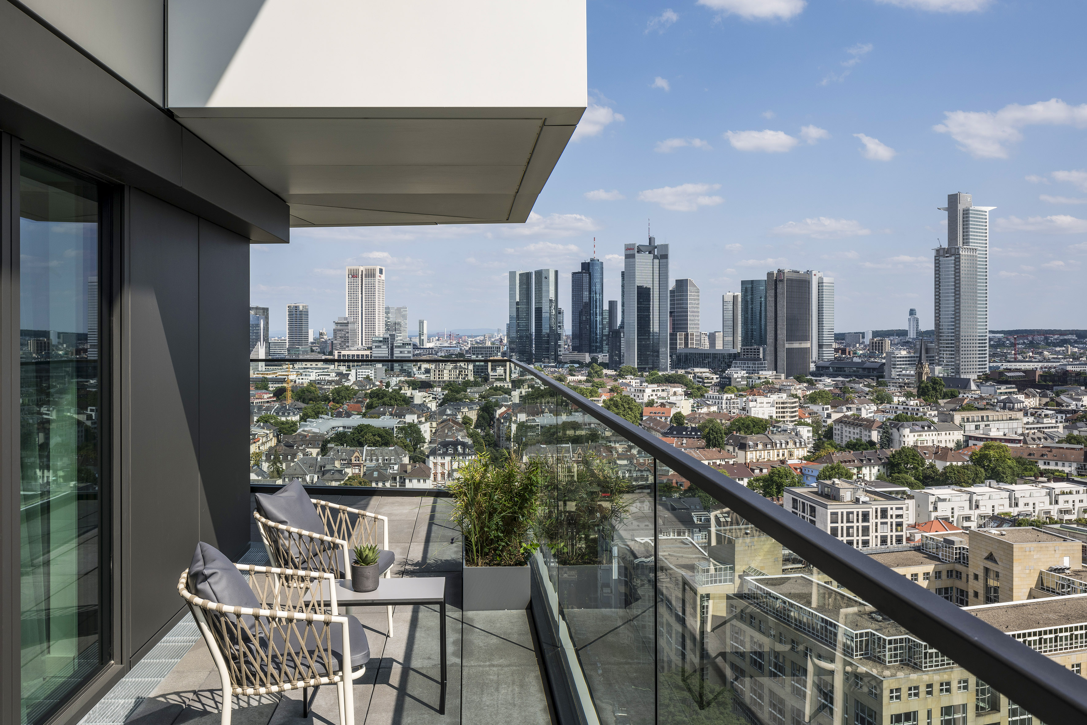 Frankfurt apartment balcony with skyline view and modern outdoor seating.