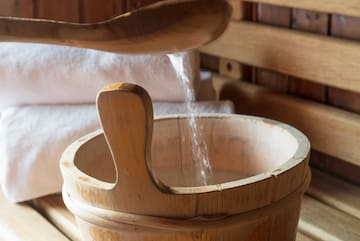 a wooden bucket with a wooden spoon pouring salt into it
