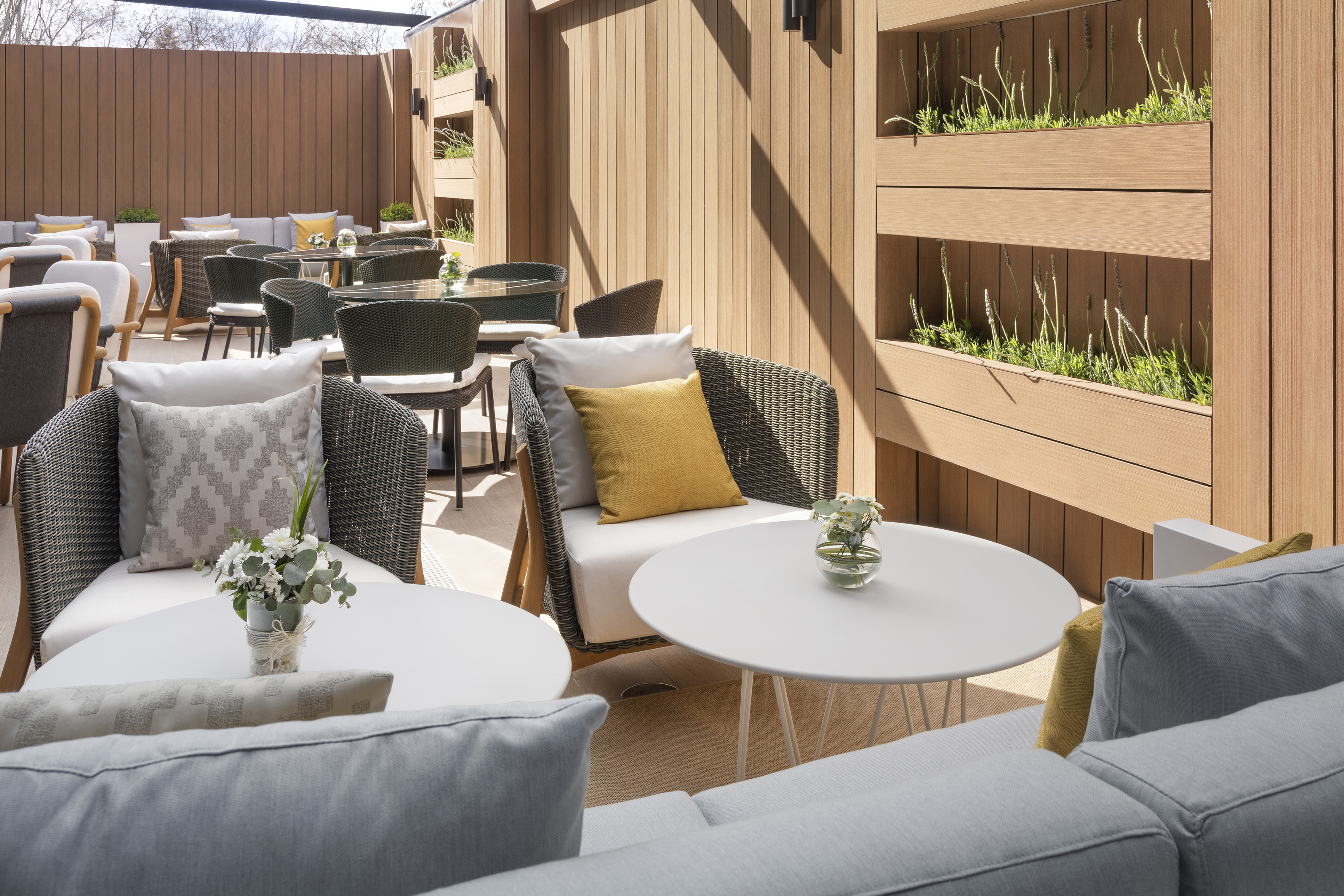 Modern outdoor lounge patio with comfortable seating and wooden wall planters.