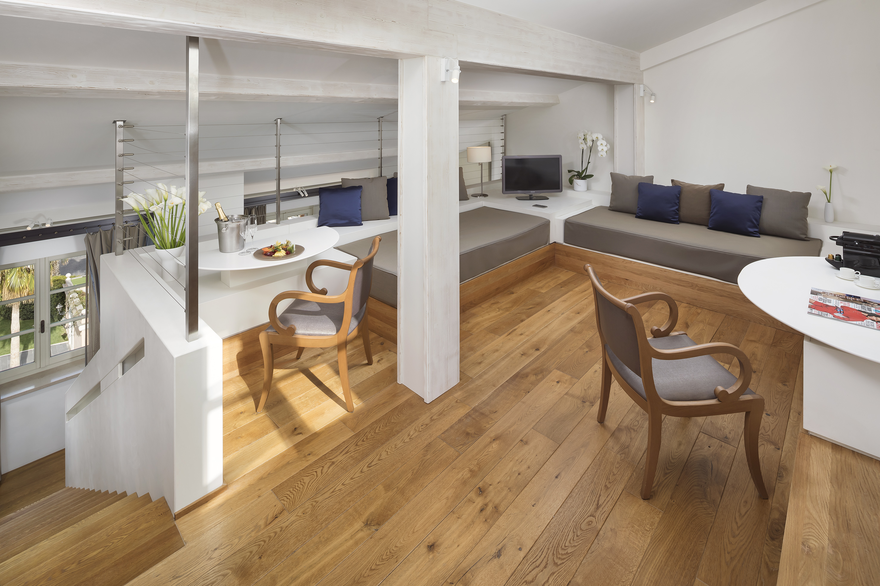 Bright split-level hotel suite with wood floors and modern cozy seating.