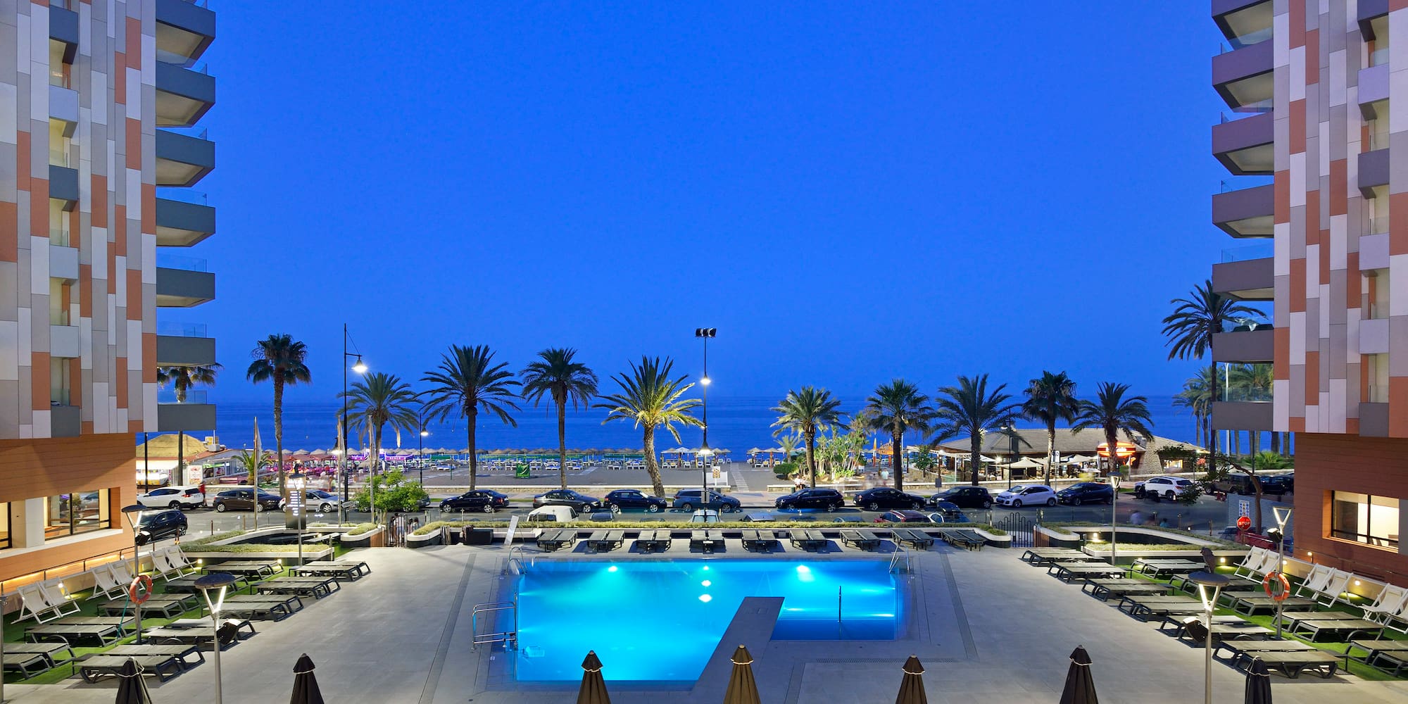 a pool with palm trees and a beach in the background