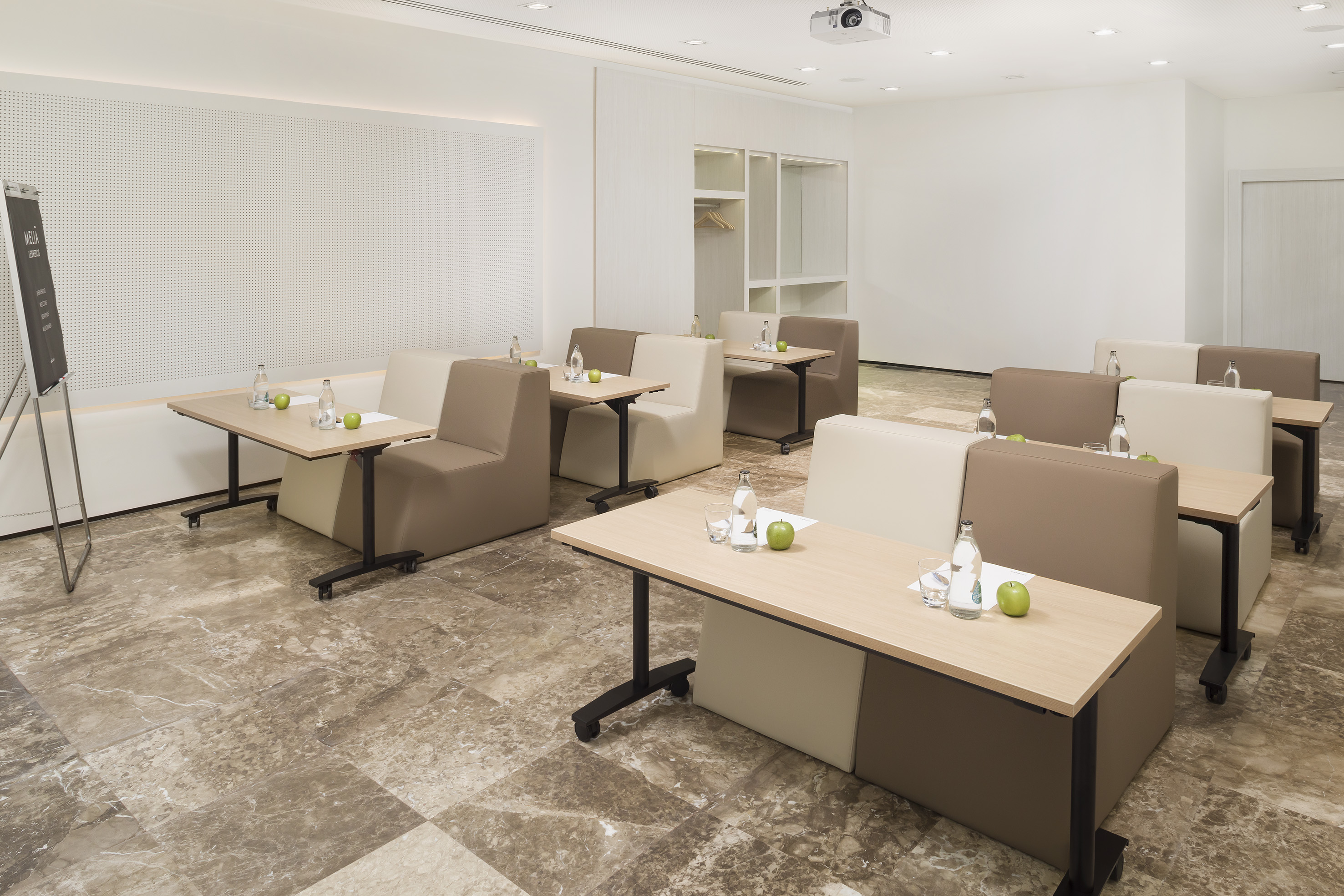 Flexible modern meeting room with modular booth seating, rolling tables, projector.