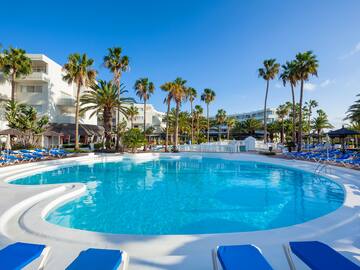 a pool with palm trees and buildings