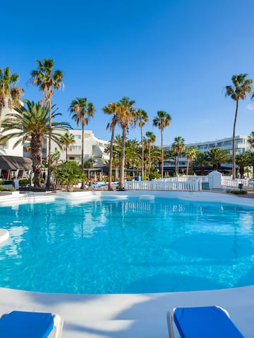 a pool with palm trees and buildings