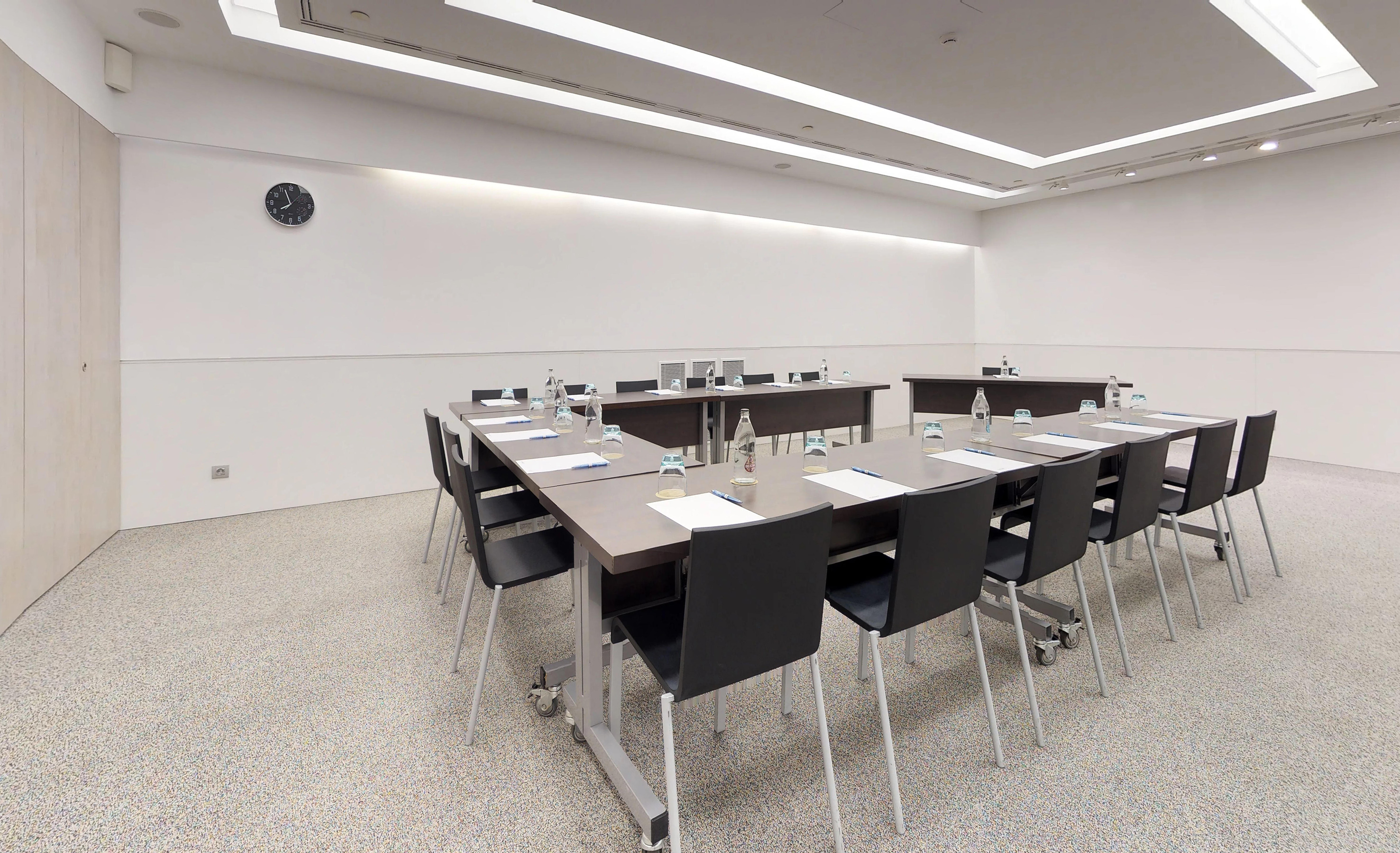 Modern conference room with U-shaped table, black chairs, and clean design.