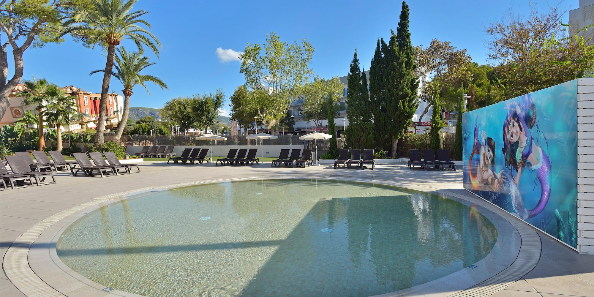 a pool with lounge chairs and trees