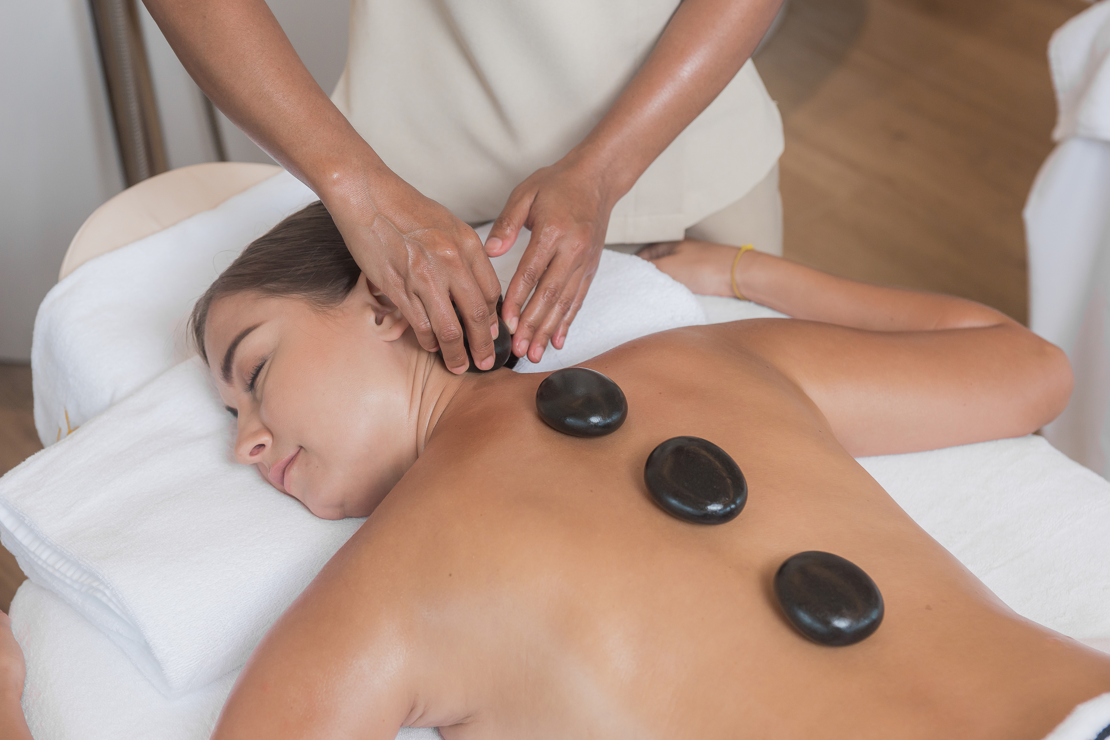 Relaxed woman receiving hot stone back massage at a tranquil spa.