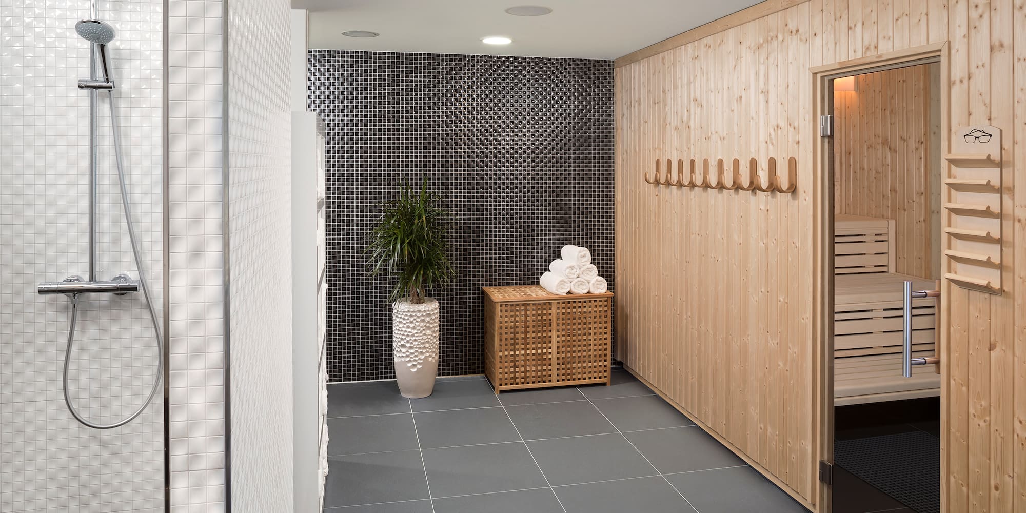 Modern wellness area with shower and wooden sauna room.