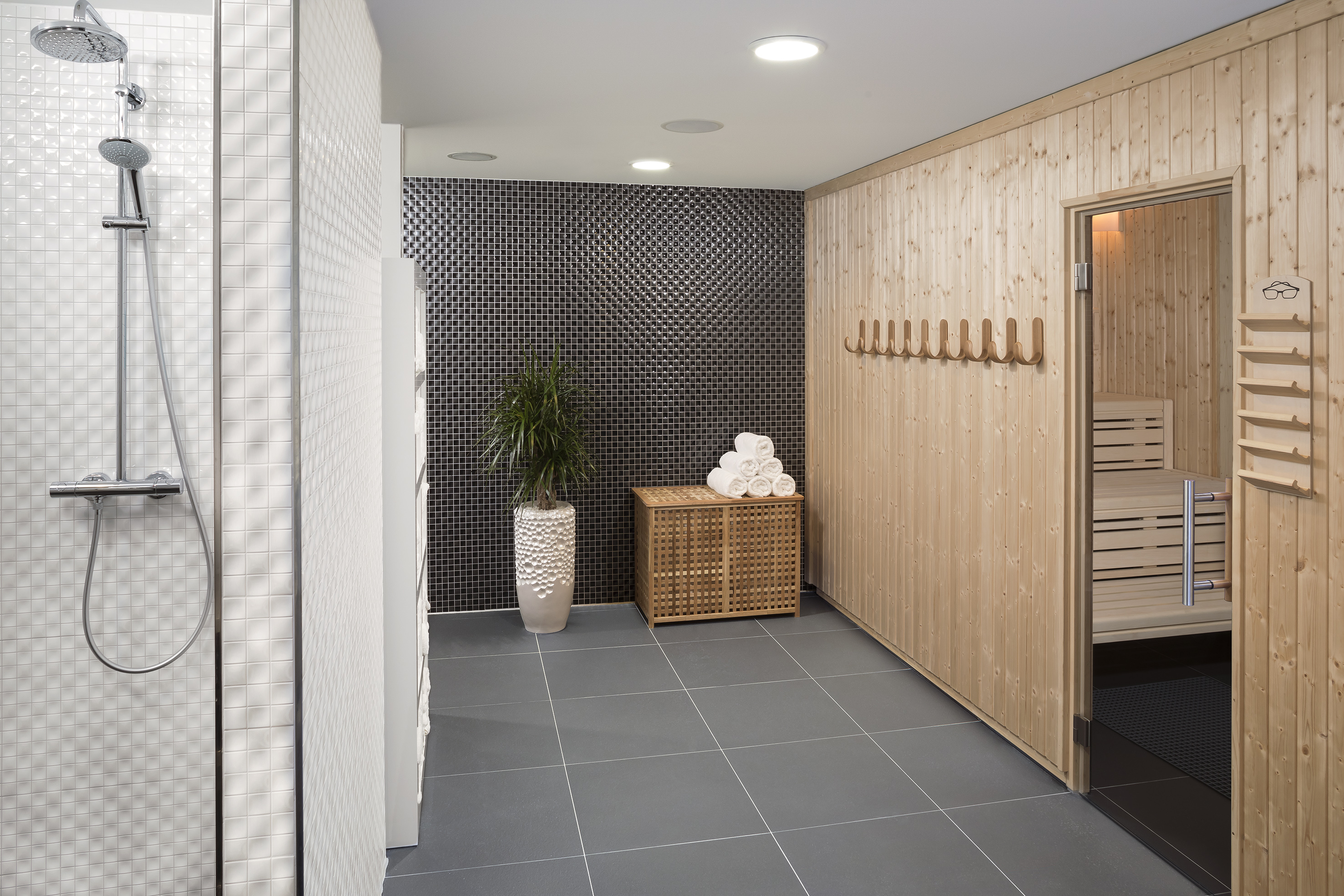 Modern wellness area with shower and wooden sauna room.