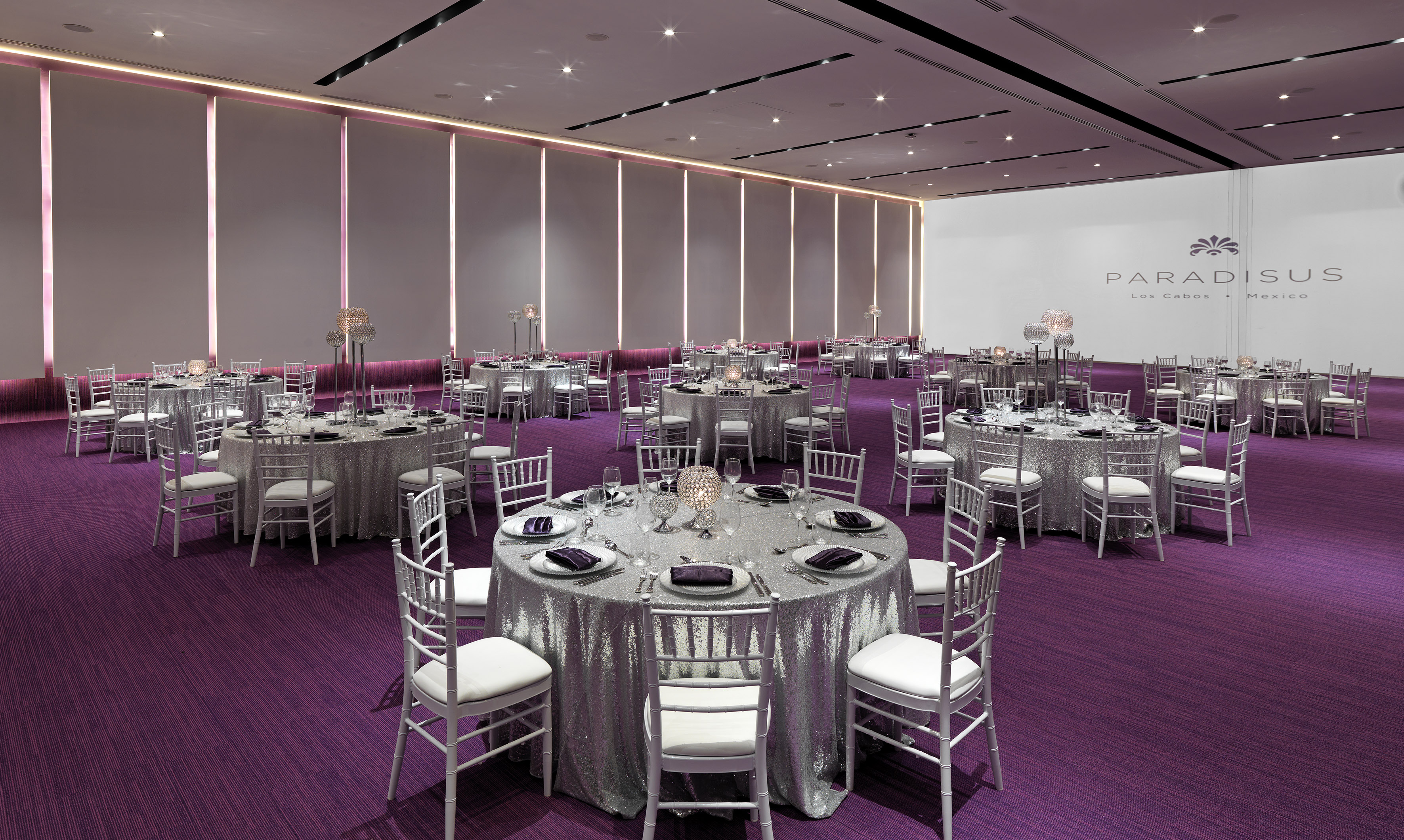 Paradisus Los Cabos elegant ballroom with silver tables, white chairs, purple carpet.