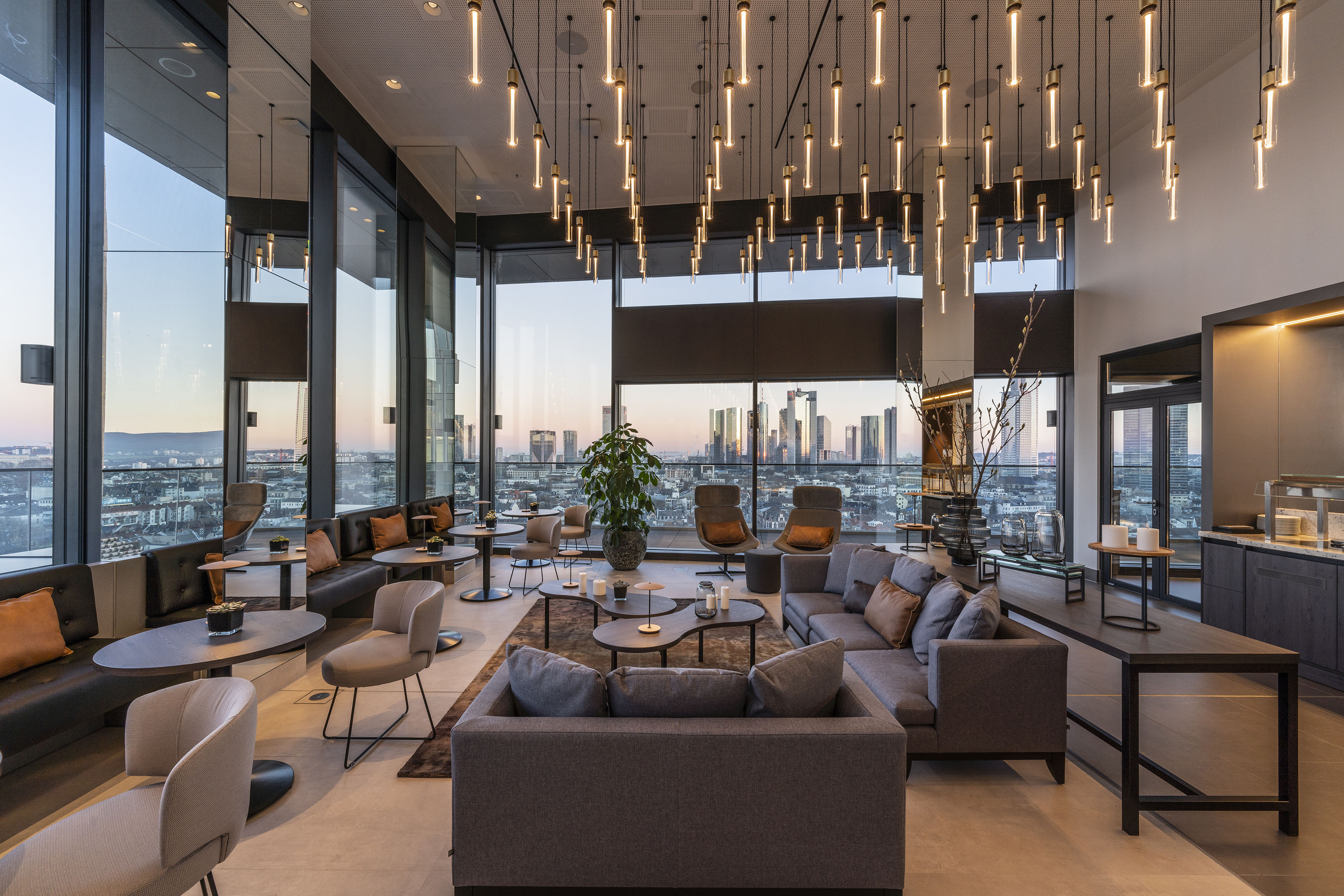 Modern lounge with Frankfurt skyline view, stylish seating, and pendant lights.