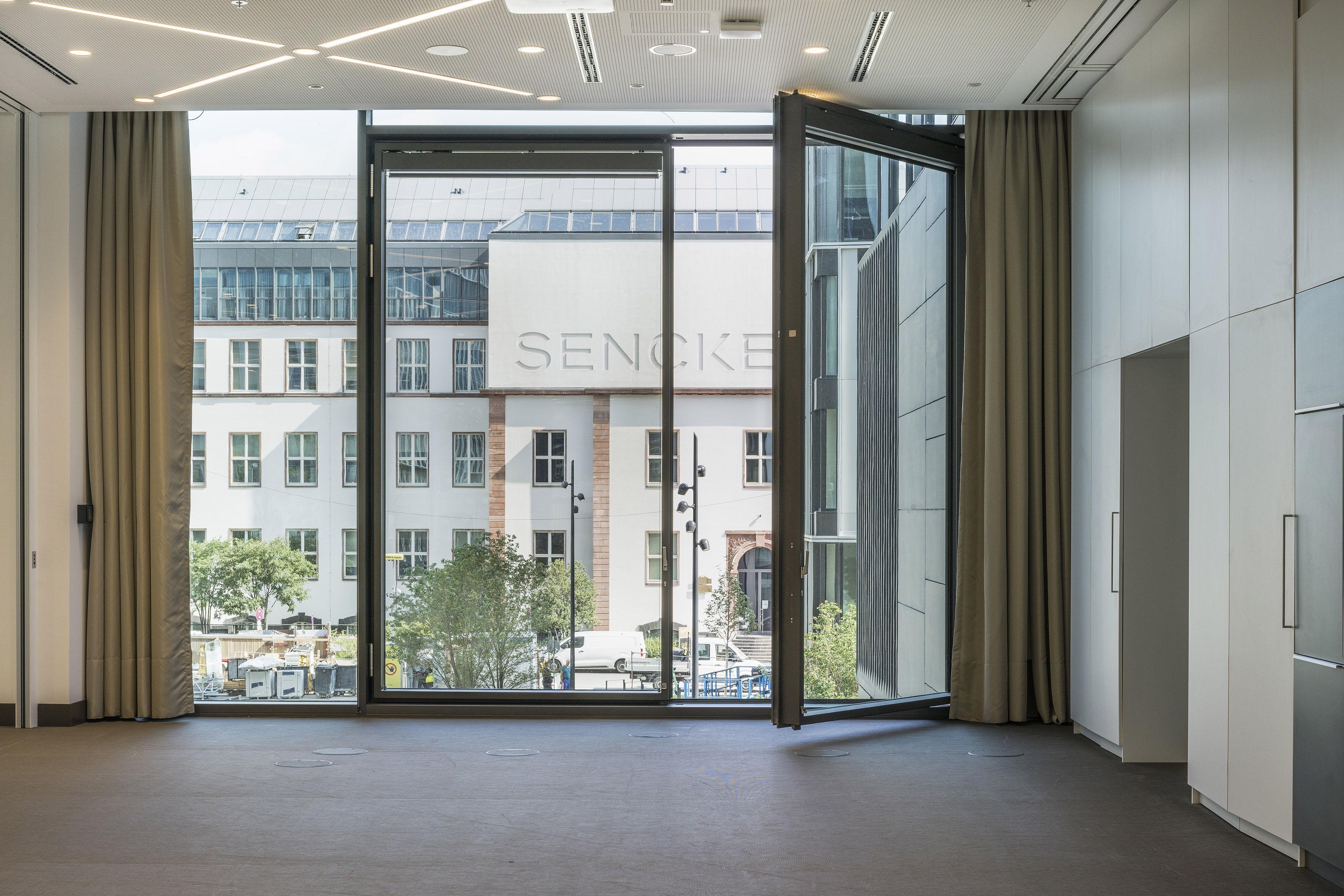 Modern room with large window, city view, and SENCKE building exterior.