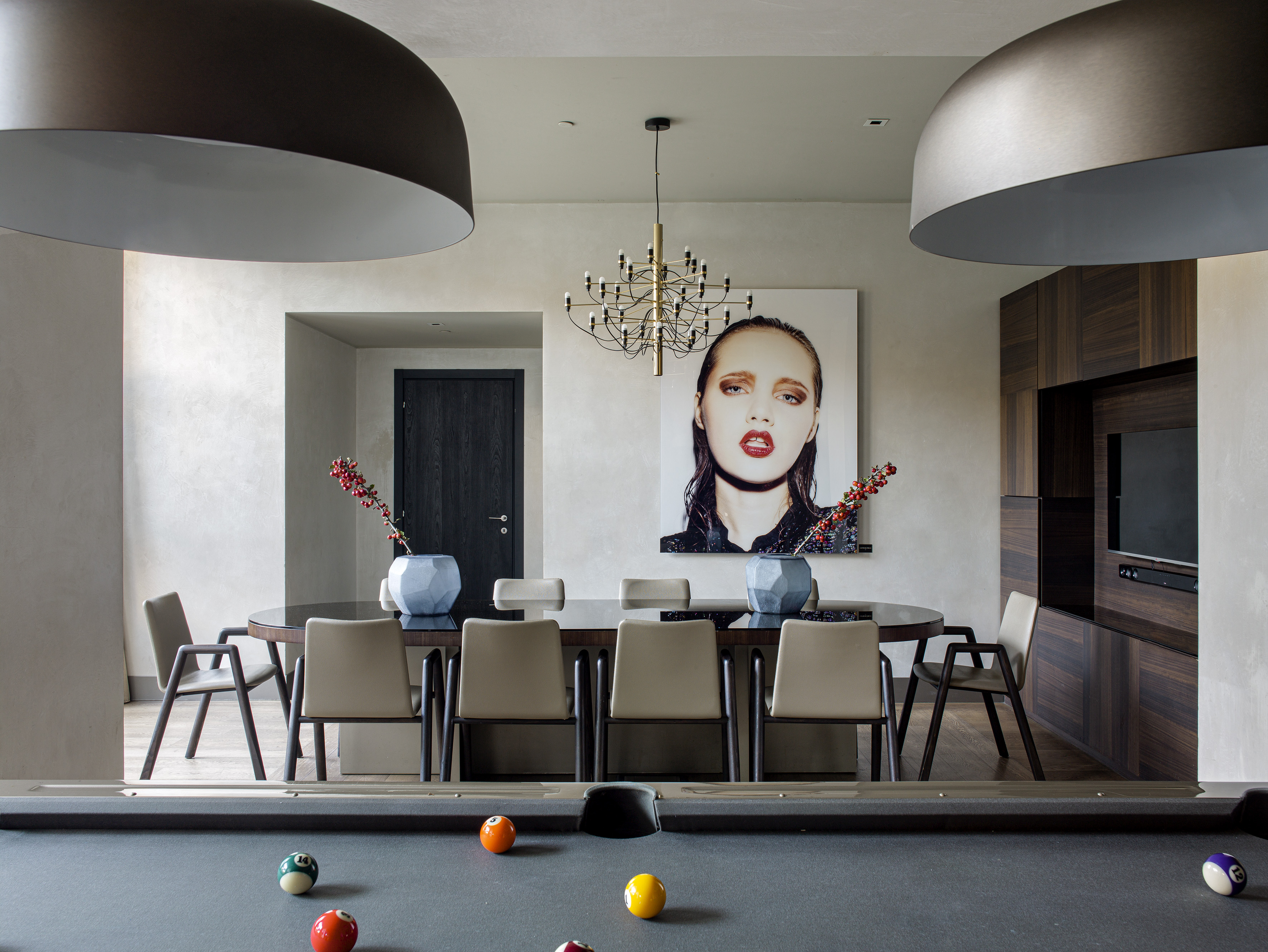 Modern dining room with contemporary art, chandelier, and pool table.