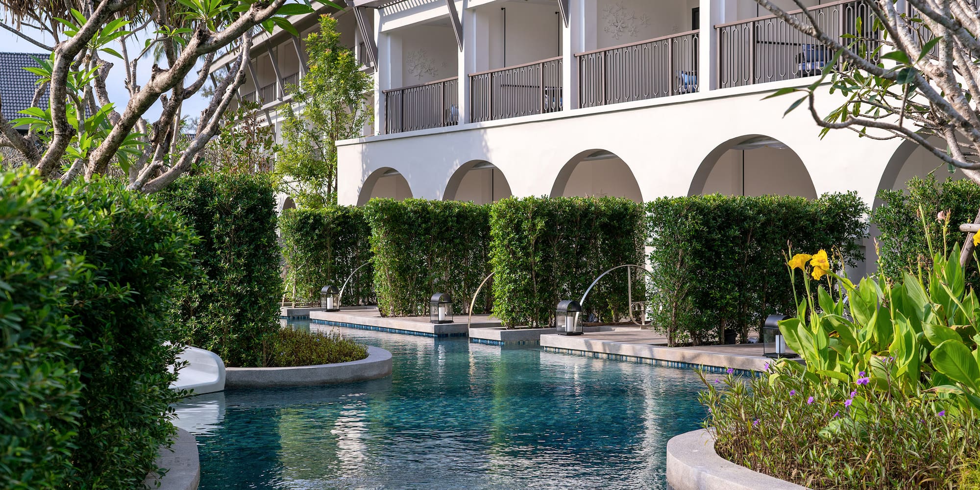 a pool with bushes and trees around it