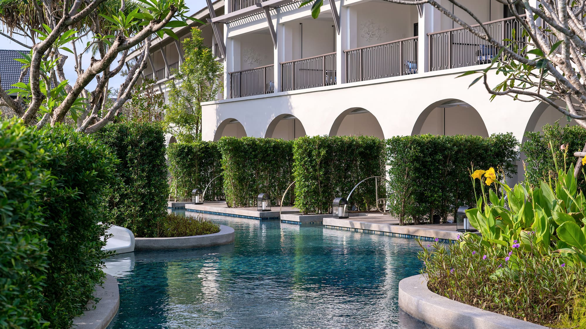 a pool with bushes and trees around it