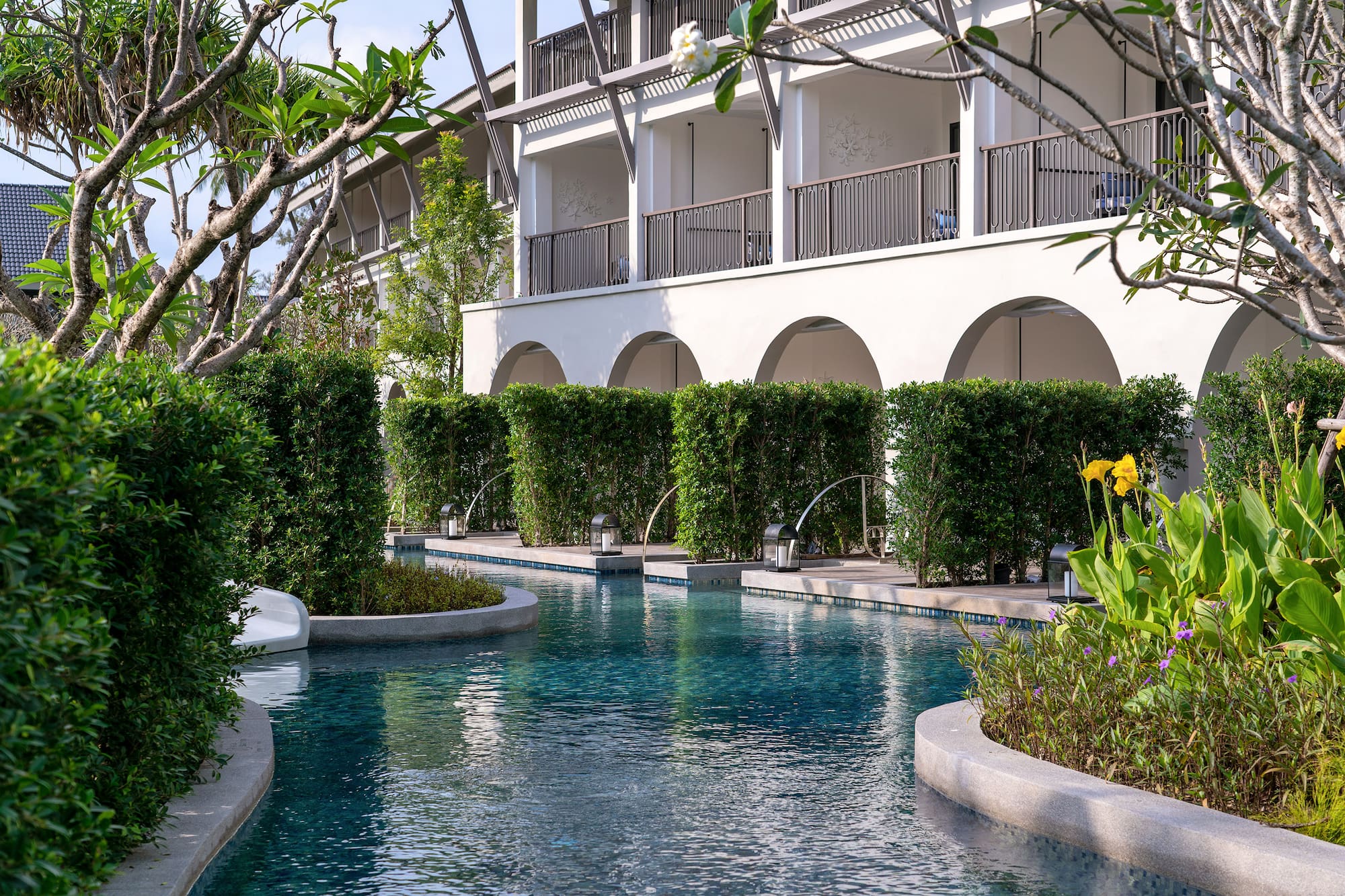 a pool with bushes and trees around it